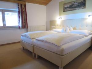 a bedroom with two beds with white sheets and a window at Apartment Hof am Schönbach-1 by Interhome in Sankt Jakob