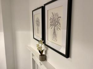 two framed pictures on a wall with a vase of flowers at Luxeurs - Victoria Street Apartments in Liverpool