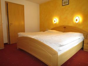 - une chambre avec un grand lit et une tête de lit en bois dans l'établissement Apartment Schmiedbach - STA255 by Interhome, à Sankt Anton am Arlberg