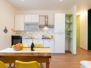 a kitchen with white cabinets and a table with a bowl of fruit at Apartment Coty - IMP522 by Interhome in Imperia