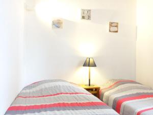 een slaapkamer met 2 bedden en een lamp op een tafel bij Holiday Home Les Charmilles-6 by Interhome in La Palmyre