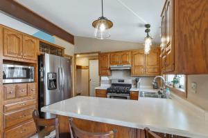 cocina con armarios de madera y nevera de acero inoxidable en Cozy Maple House Family Lake Como Retreat, en Lake Geneva