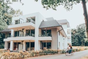 a woman riding a bike in front of a house at Holiday Suites Limburg in Aan de Wolfsberg