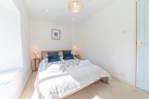 Dormitorio blanco con cama con almohadas azules en Vicarage Barn 