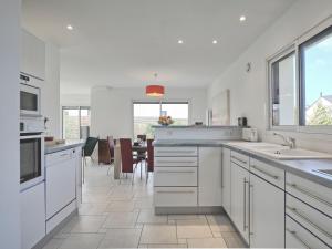 cocina con armarios blancos y comedor en Holiday Home Golf de Bretagne - RHU354 by Interhome, en Sarzeau