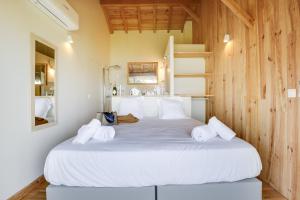 a large white bed in a room with wooden walls at Villa Mimbeau in Cap-Ferret