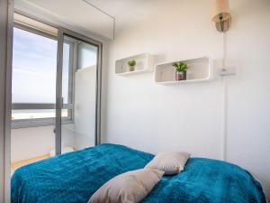 a bedroom with a blue bed with a large window at Apartment Les Trois Mâts-4 by Interhome in Canet-en-Roussillon
