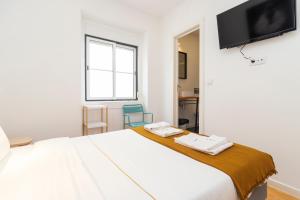 a bedroom with a large white bed and a flat screen tv at Gloria 10 in Lisbon