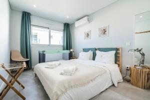 a bedroom with a large white bed and a chair at Coastal Holiday´s Apartment in Monte Gordo