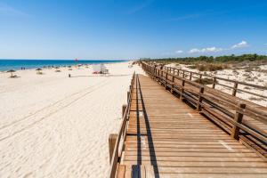 a wooden boardwalk on a beach with the ocean at Coastal Holiday´s Apartment in Monte Gordo