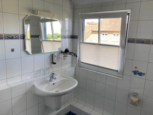 ein Bad mit einem Waschbecken, einem Spiegel und einem Fenster in der Unterkunft Gästehaus Kölfhamm 2 in Sankt Peter-Ording