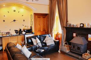 a living room with a leather couch and a stove at Gowanlea Heights in Campbeltown