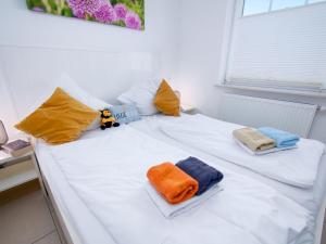 ein weißes Bett mit Handtüchern und Kissen darauf in der Unterkunft Apartment Küstenoase by Interhome in Norddeich