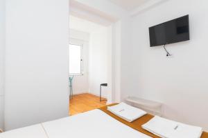 a white room with two beds and a flat screen tv at Gloria 10 in Lisbon