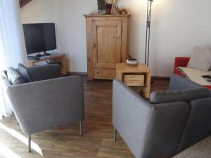 a living room with two chairs and a tv at Apartment Bierlialp-Park A35 by Interhome in Engelberg