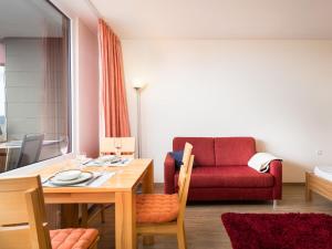 sala de estar con mesa y sofá rojo en Apartment B906 by Interhome, en Lahnstein