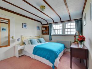 um quarto com uma cama, uma secretária e janelas em Holiday Home Eglos by Interhome em Saint Merryn