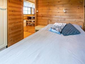 KoluにあるHoliday Home Kalliorinne by Interhomeの木製キャビン内の白いベッド1台が備わるベッドルーム1室です。
