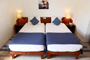 two beds in a hotel room with blue pillows at Mira Parque in Albufeira