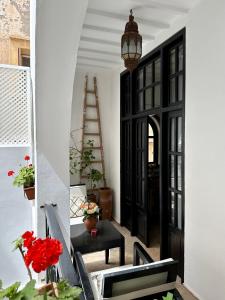 un escalier avec une porte noire, une table et des fleurs dans l'établissement Riad Dar Awil, à Essaouira