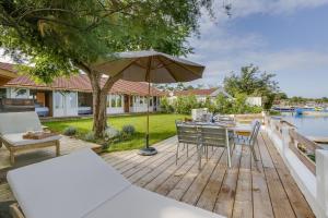 a wooden deck with a table and chairs and an umbrella at Villa Mimbeau in Cap-Ferret