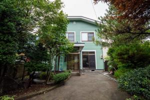 a blue house with a driveway in front of it at Immaculate Private Family Cottage with Hot Spring in Towada