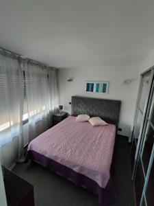 een slaapkamer met een paars bed met 2 kussens bij CARRY-LE-ROUET PLAGE in Carry-le-Rouet