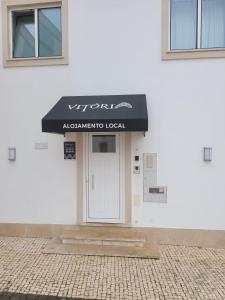 een wit gebouw met een zwarte luifel op de deur bij Alojamento Local Vitoria in Batalha