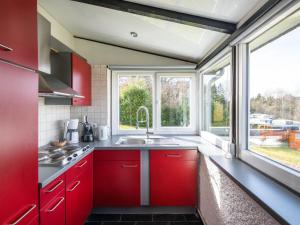 cocina con armarios rojos y ventana grande en Holiday Home Waldferienpark Gerolstein-12 by Interhome, en Gerolstein