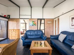 sala de estar con sofás de cuero azul y mesa de centro. en Holiday Home Waldferienpark Gerolstein-12 by Interhome, en Gerolstein