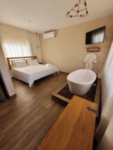uma casa de banho com uma cama e uma banheira num quarto em Euetu na Lapinha da Serra em Santana do Riacho