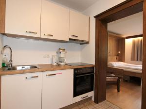 cocina con armarios blancos, fregadero y cama en Apartment Römerhof-5 by Interhome en Fügen