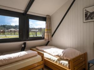 2 Betten in einem Zimmer mit 2 Fenstern in der Unterkunft Holiday Home Waldferienpark Gerolstein-16 by Interhome in Gerolstein