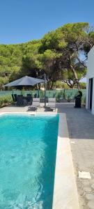 a swimming pool with chairs and an umbrella at Valverde 2 Villa, Vilamoura, Algarve, only 5 minutes from Marina, Golf and Beach in Vilamoura
