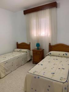 a bedroom with two beds and a table with a lamp at UNIFAMILIAR SIERRA DE CADIZ in El Bosque