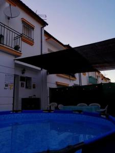 a swimming pool with an umbrella in front of a house at UNIFAMILIAR SIERRA DE CADIZ in El Bosque