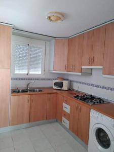 a kitchen with wooden cabinets and a sink and a microwave at UNIFAMILIAR SIERRA DE CADIZ in El Bosque