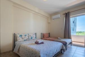 a bedroom with two beds and a large window at Elia mini suites 7 in Larisa