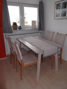 uma mesa de jantar e cadeiras com uma mesa e janelas em Fewo Am Heidestrandbad em Hemmoor