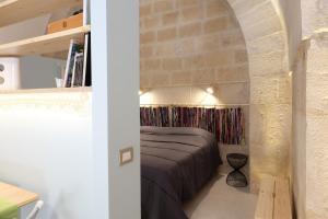 een slaapkamer met een bed en een bakstenen muur bij Sottano del Mastro Central Apartment in Corato