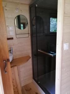 a bathroom with a glass shower in a tiny house at Roulotte La Vert-Dîne in Saint-Pardoux