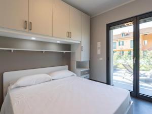 a bedroom with a white bed and a sliding glass door at Apartment Ormeasco by Interhome in Imperia