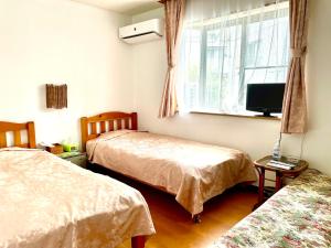 a bedroom with two beds and a tv and a window at タートルハウス in Shimoda