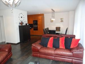 ein Wohnzimmer mit einem braunen Ledersofa mit Kissen in der Unterkunft Apartment Bellevue-Park B 145 by Interhome in Engelberg