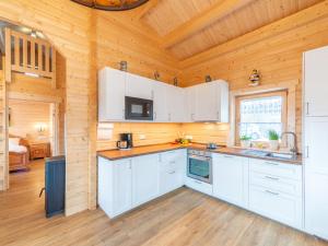 una cucina con armadi bianchi e soffitto in legno di Holiday Home Chalet Toni mit Sauna by Interhome a Spiegelau