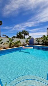 una gran piscina azul con palmeras en el fondo en Beachfront house,Manta Rota,Algarve, en Vila Nova de Cacela