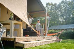 Un ragazzo in piedi sul portico di un gazebo di Glamping Twente a Denekamp