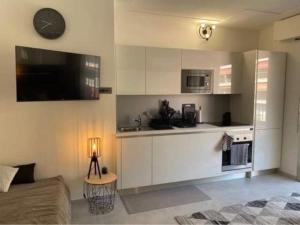 a kitchen with white cabinets and a television in a room at Studio Residence de la Plage, au bord de la mer in Menton +15 photos