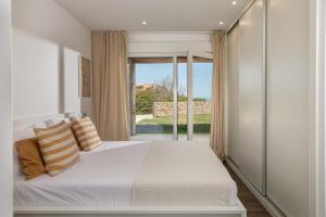ein Schlafzimmer mit einem weißen Bett und einem großen Fenster in der Unterkunft Casa Ciudamar Costa Brava - BY EMERALD STAY in Begur