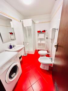 uma casa de banho vermelha com 2 WC e uma máquina de lavar roupa em Falcone 22 em Bolonha